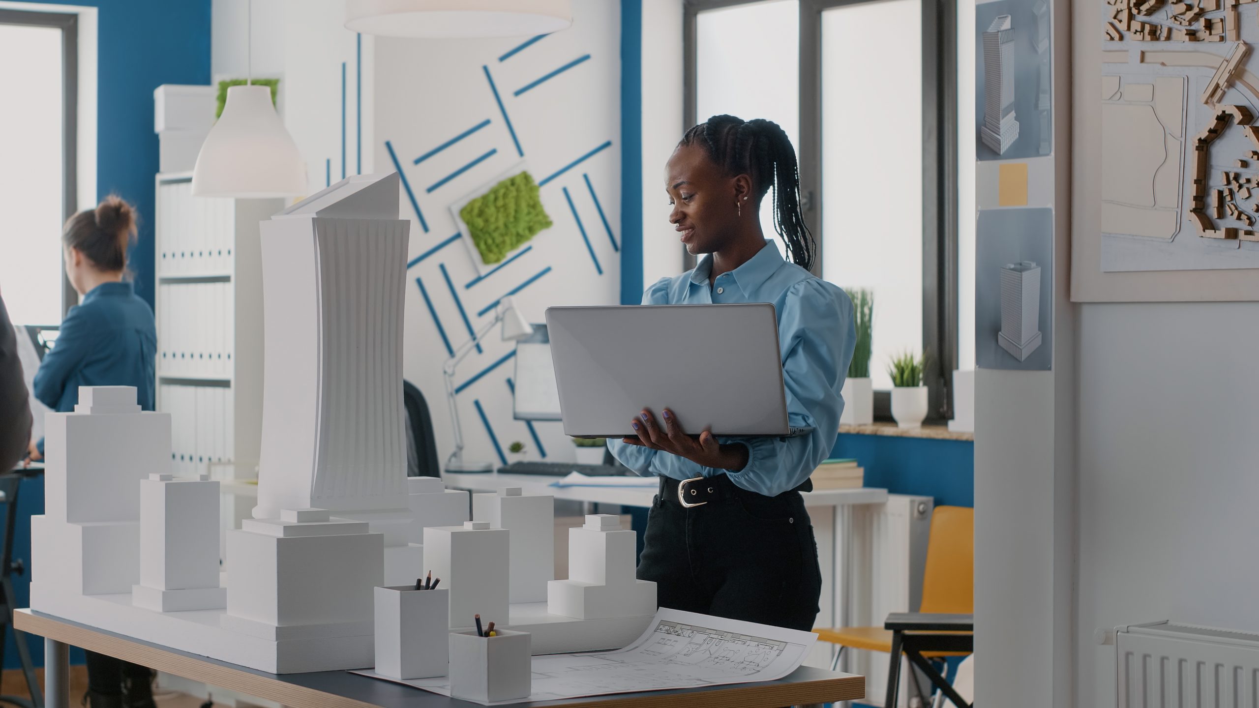 Services 14 Woman architect holding laptop to analyze building model in architectural office. Engineer working with computer and maquette to design construction structure for urban project.